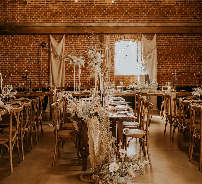 Bohemian luxe wedding reception decor in a barn with dried flowers, festoon lights, rope and natural fabrics 