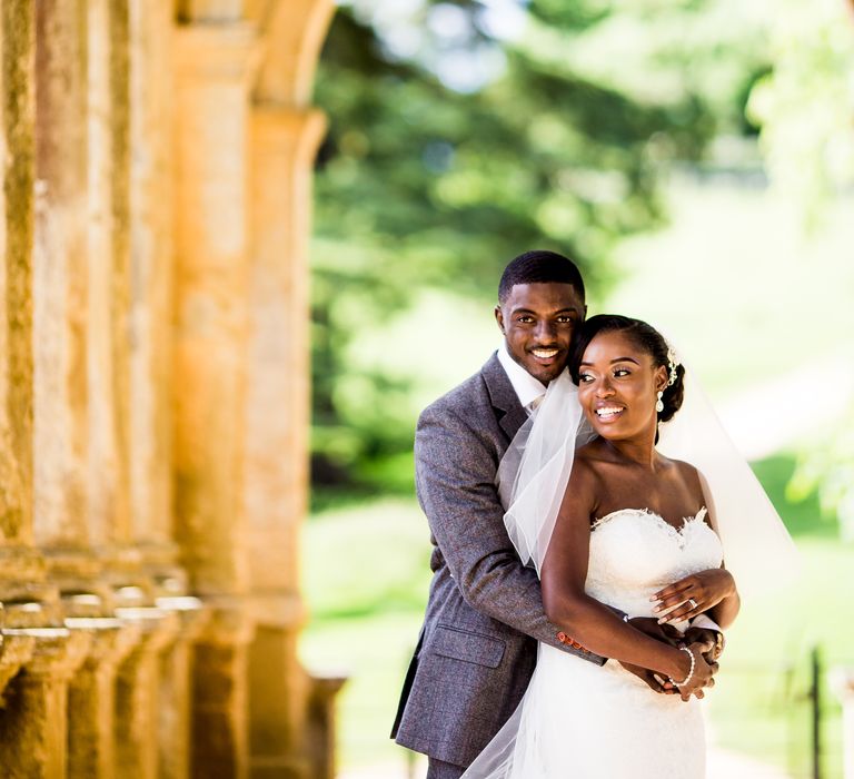 Black bride & groom stand beneath golden arches