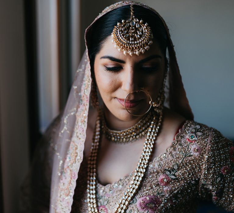 Bride stands beside window and looks down