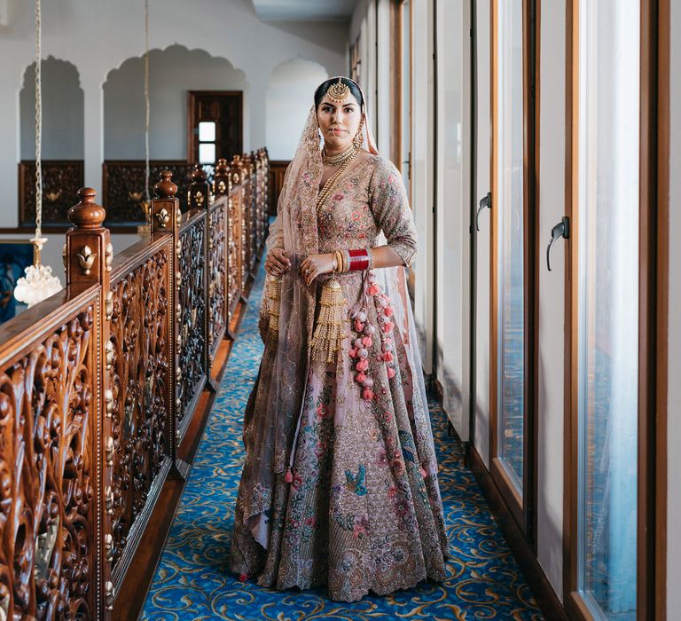 Bride stands in hallway wearing beautifully embellished lehengha 