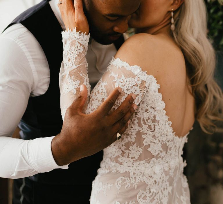 Bride kissing the groom's cheek as he holds her arm and hugs her