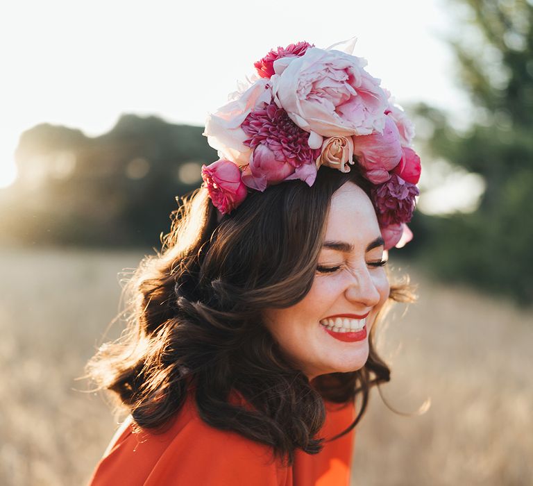 Bride wears her dark hair in curls and with a pink floral crown