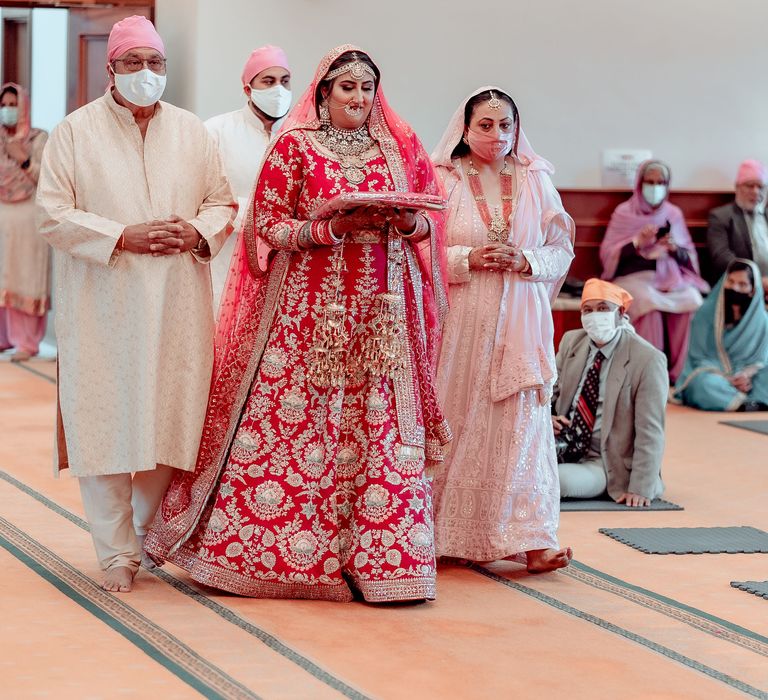 Bride walks into ceremony with family members on the day of her wedding