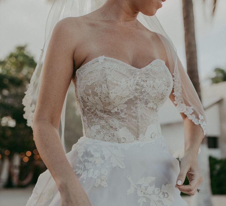 Bride wears lace gown with sweetheart neckline and lace lined wedding veil