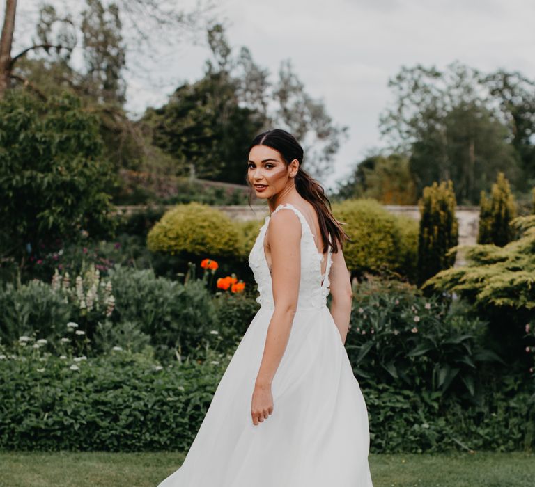 Beautiful bride with a sleek ponytail in a Suzanne Neville Nova 2022 wedding dress with appliqué bodice and full skirt 