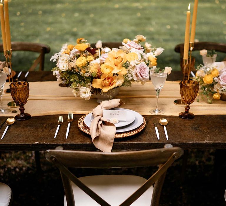 Honey yellow wedding inspiration with yellow flowers, gold candlesticks and wicker place mat table decor 