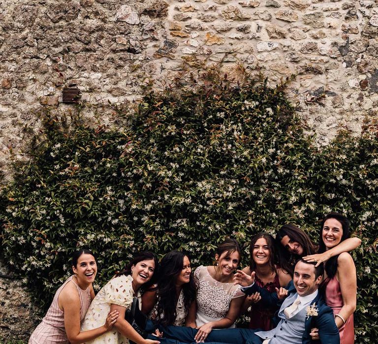 Groom in blue suit is held up by wedding guests and bride in Rime Arodaky wedding dress for summer wedding in Dorset