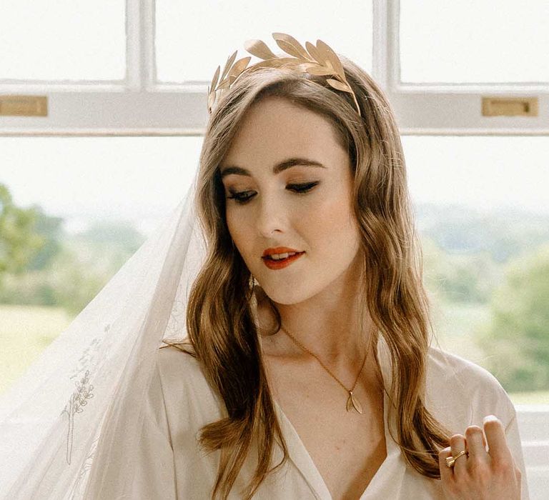 Bride in a wheelchair on the wedding morning in a getting ready robe with feather cuff detail, lace veil and gold crown headdress