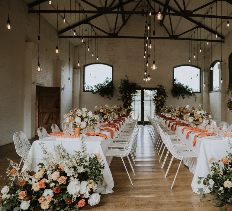 Osea Island wedding reception decor with white metal chairs, orange napkins and peach wedding flowers 