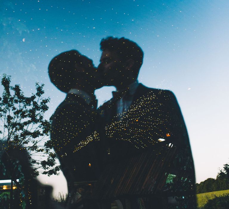 Grooms kiss in the reflection of window  | Story + Colour