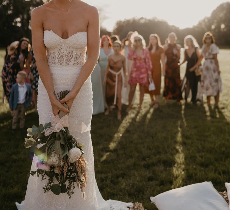 Bride prepares to throw her bouquet as wedding guests stand behind her at Duddon Mill Farm | Mark Bamforth Photography