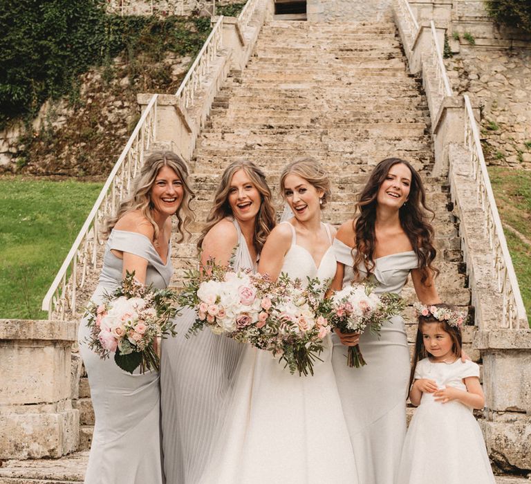 Bridal party portrait on the steps of Chateau Lagorce with bridesmaids in grey dresses and the bride in an A-line Stella York wedding dress