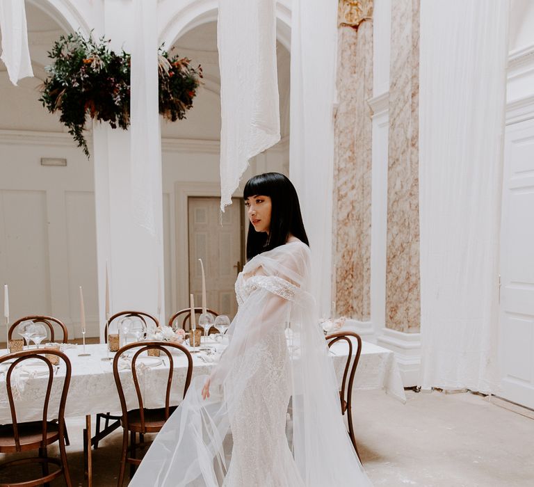 Stunning South Asian bride in an embellished wedding dress with chiffon scarf standing in the wedding reception at Bylaugh Hall 