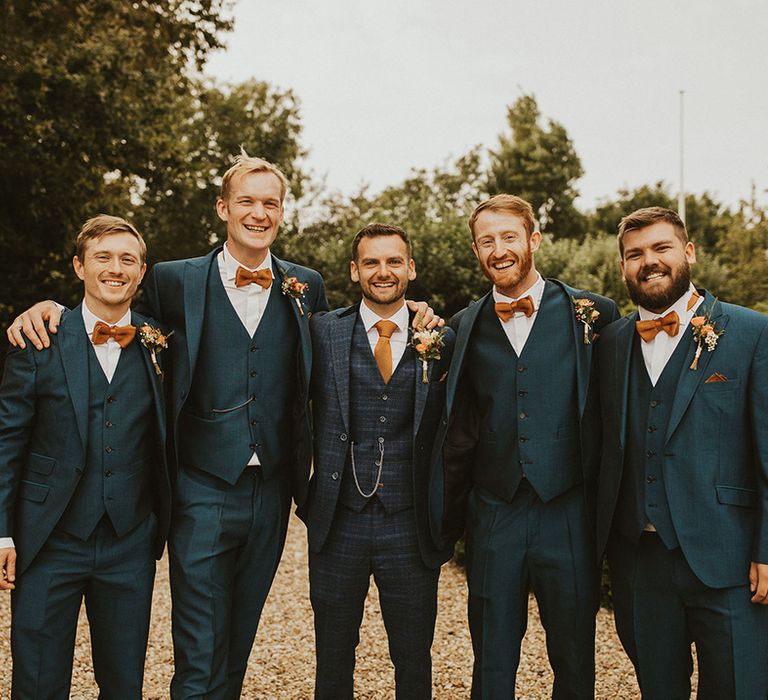 Groomsmen in matching blue suits with orange ties