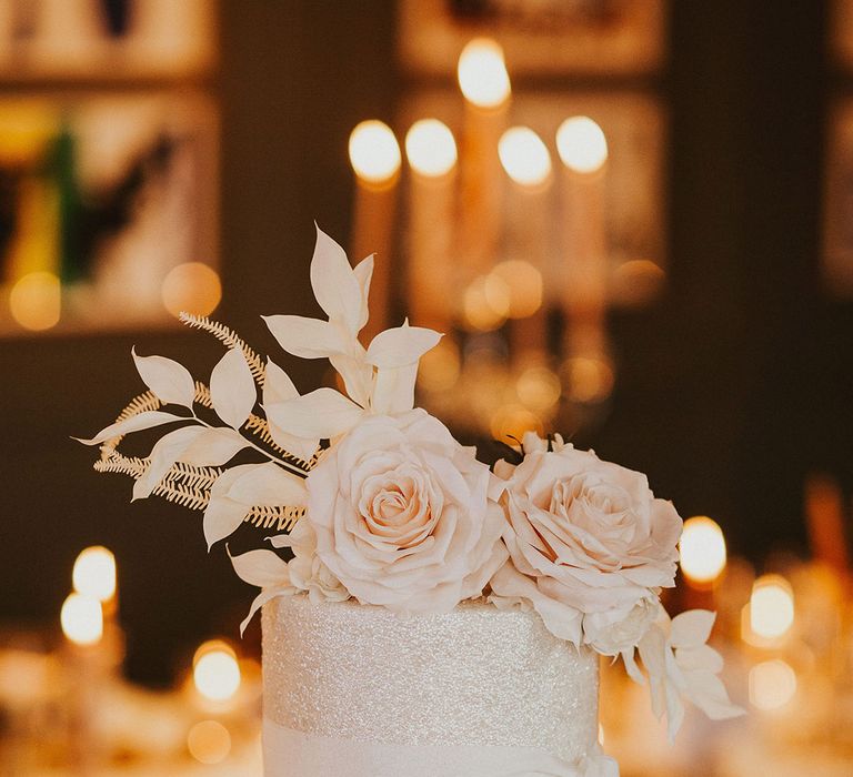 single tier wedding cake on a cake stand with ribbon and flower decor 