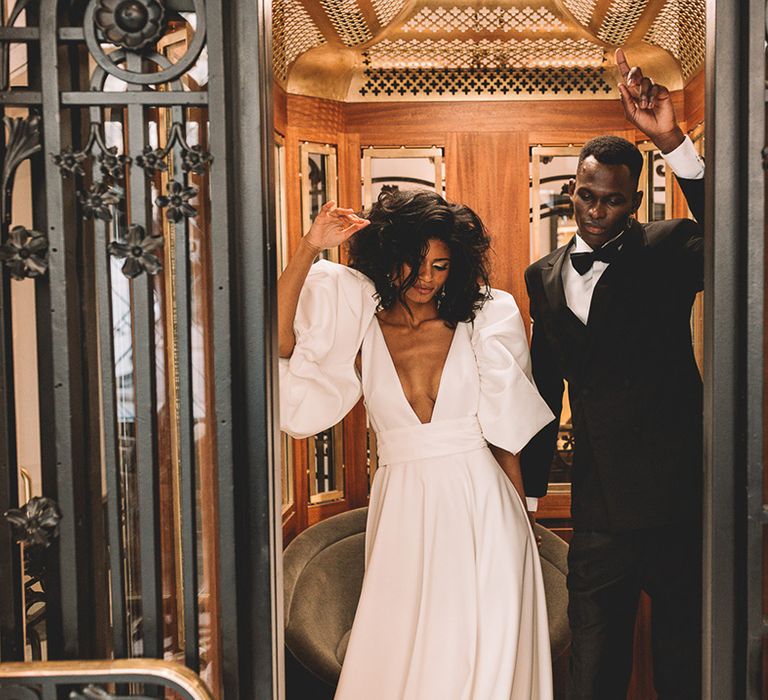 Stylish bride and groom in a tuxedo and princess wedding dress standing in a lift at he Kimpton Saint Honoré hotel in Paris 