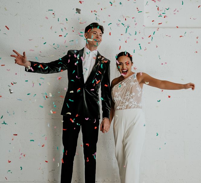 Bride & groom stand with one another in front of white wall on their wedding day