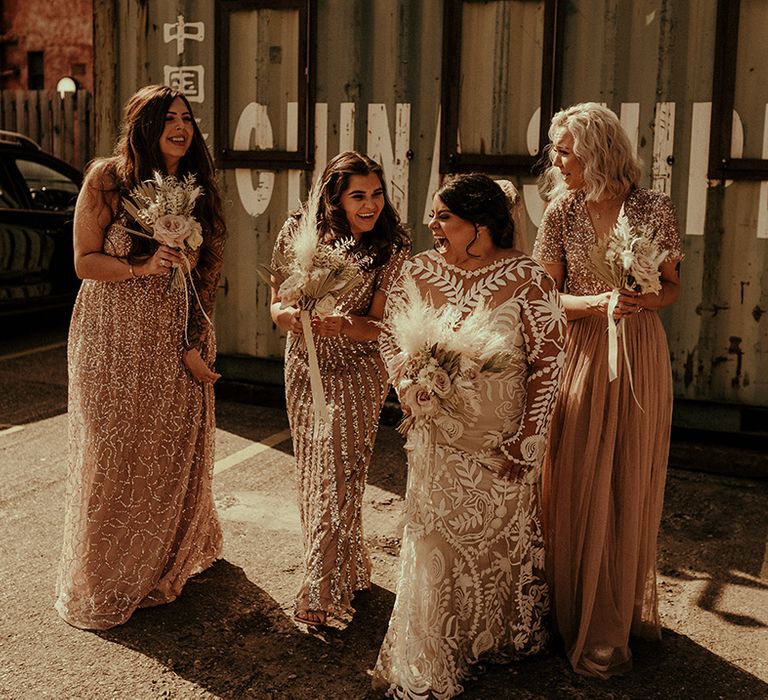 Bride and bridesmaids with the bride in a lace wedding dress and bridesmaids in blush bridesmaid dresses at Manchester wedding 