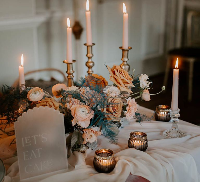 wedding table decor with gold candlesticks, taper candles, votives, blush flowers and a frosted acrylic wedding sign 