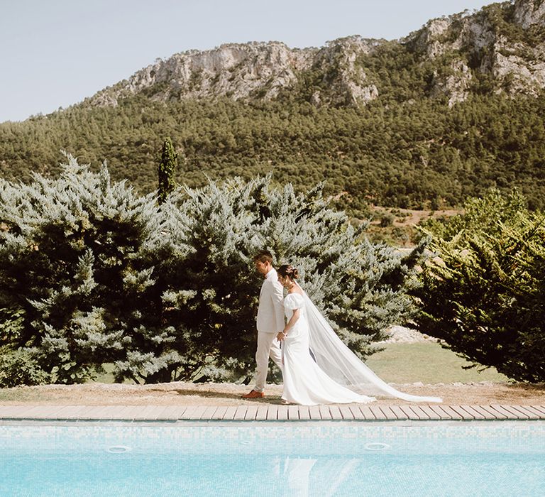 Bride and groom walking next to swimming pool