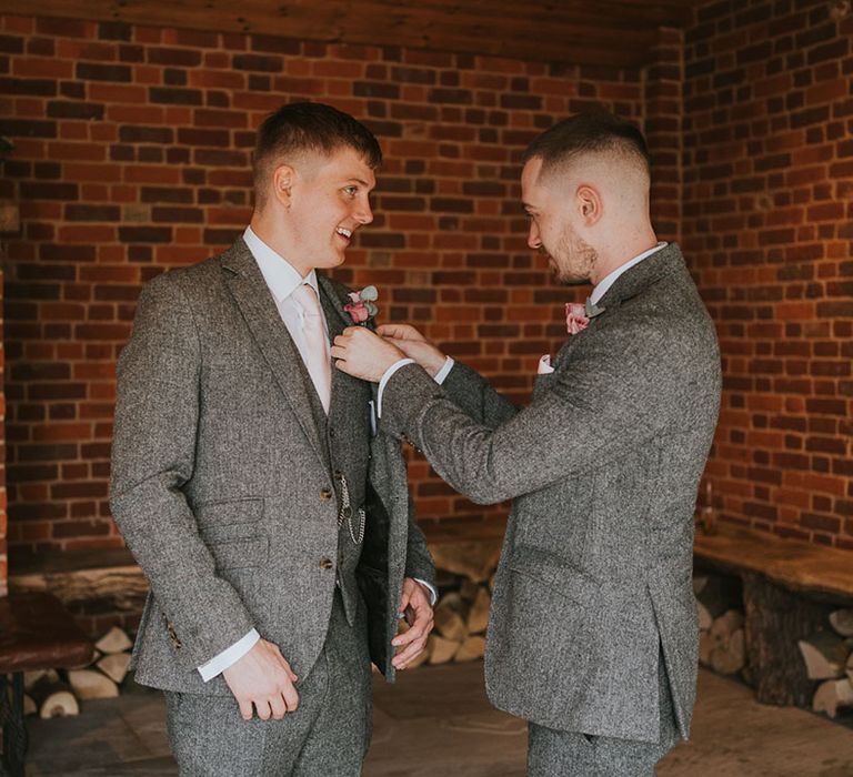 Groom and groomsman in matching grey tweed suits and pink rose boutonnières