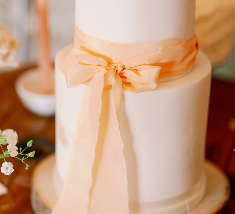 Simple and white two tier wedding cake with pink bow decoration 