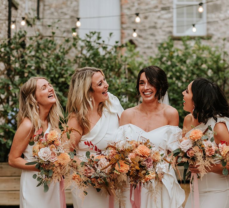 Bride in off the shoulder puff sleeve wedding dress with four bridesmaids in white one shoulder dresses