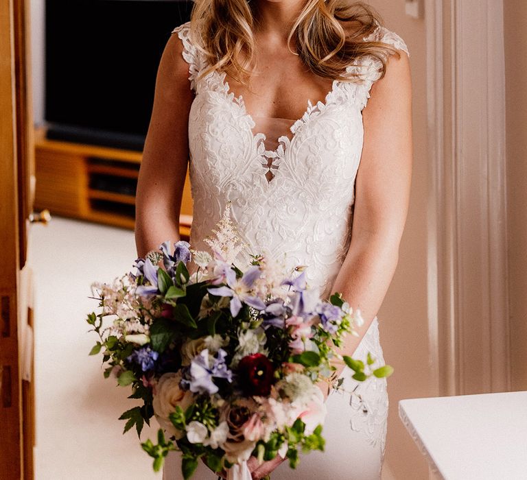 Bride in classic lace wedding dress with pink and purple bouquet with pearl drop earrings and pearl headpiece 