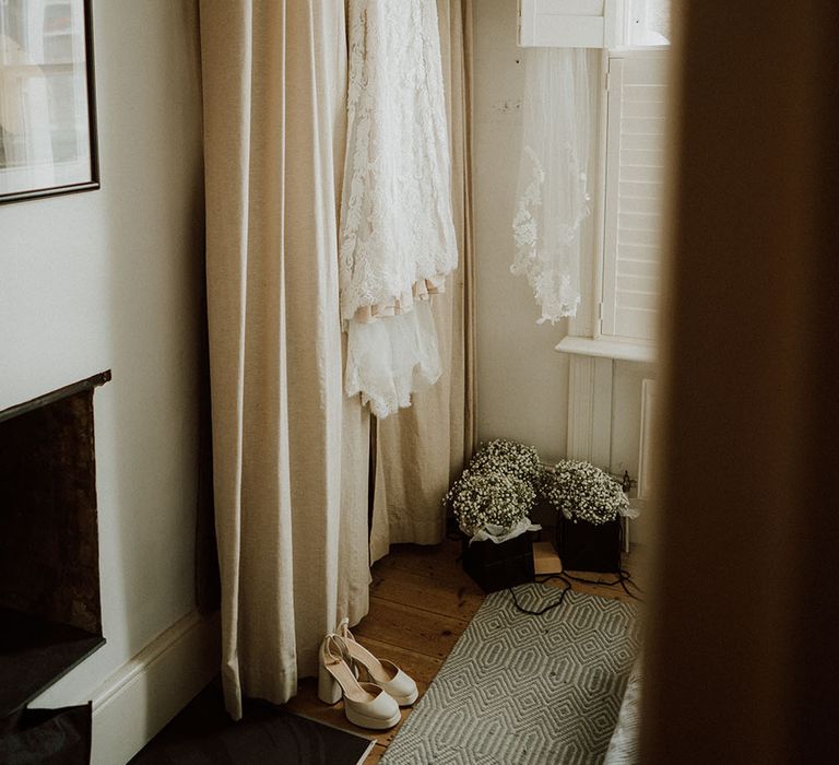 Lace wedding dress with long sleeves hangs the morning before wedding ceremony 