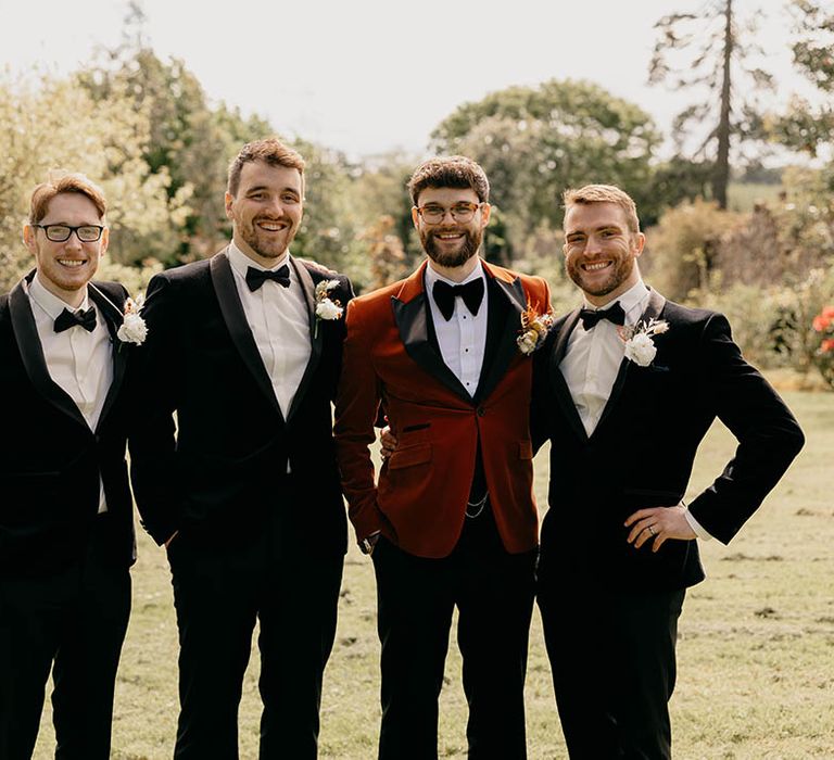 Groom in orange tuxedo with groomsmen in black tie for the retro style wedding 