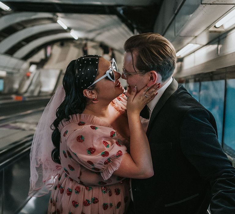 Bride wears pink veil and kisses her groom on the escalator within the tube for city wedding