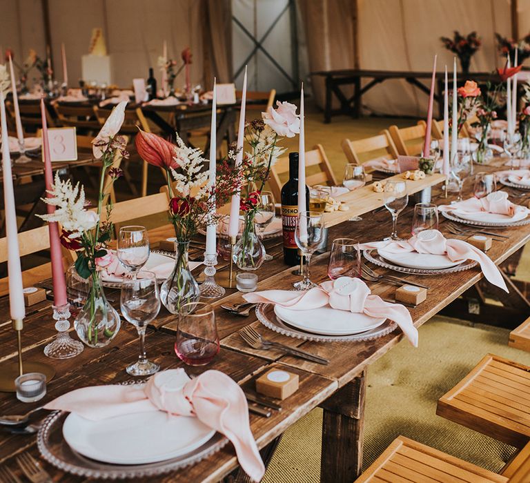 Pink wedding table setting with roses and anthuriums, taper candles, napkins and clay name places 