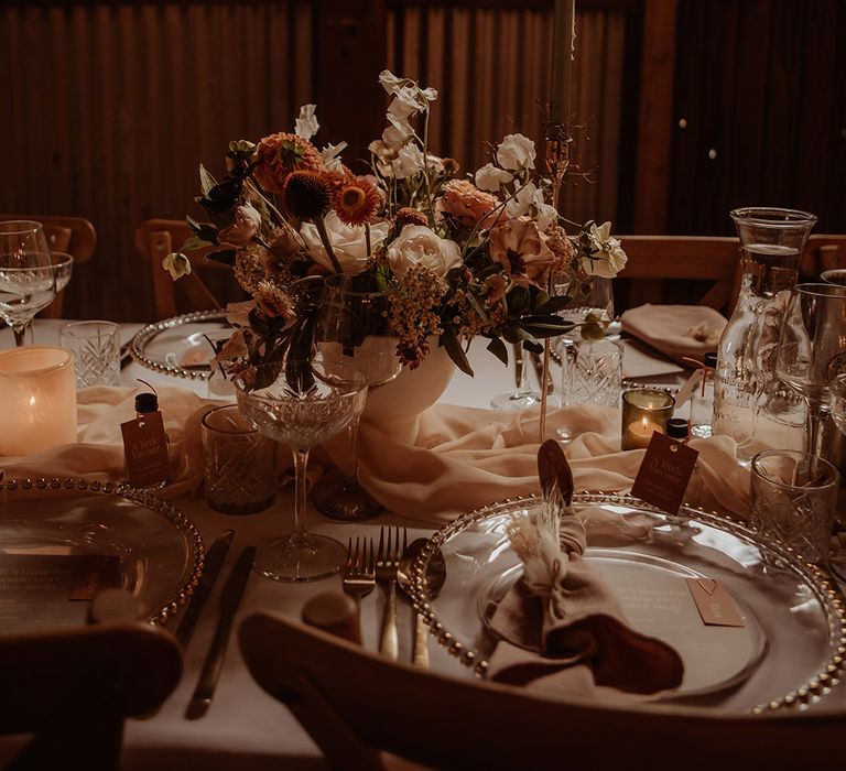 Blush pink and white wedding flower arrangement with blush table runner, gin favours, and gold cutlery and charger plates