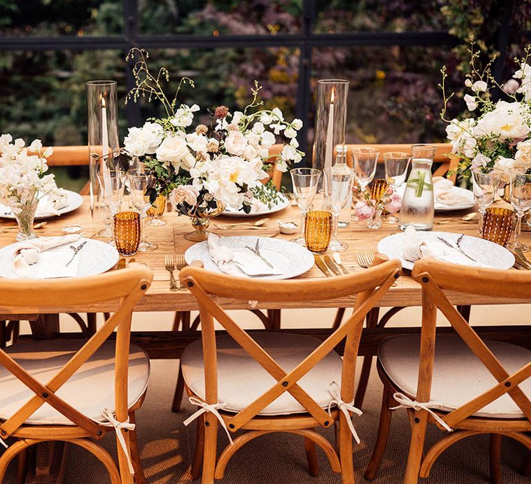 Pink and white wedding flower arrangements with taper candles on wooden banquet tables 