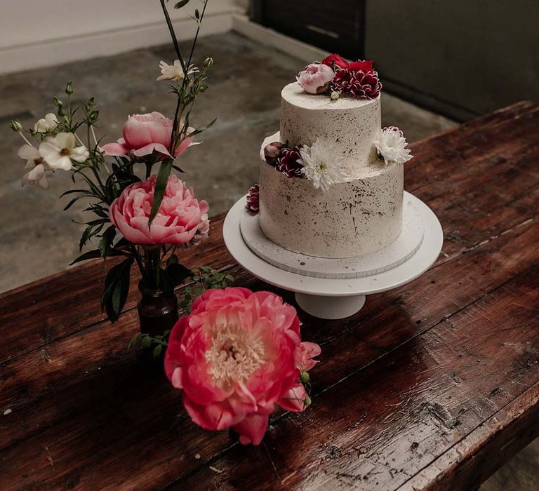 Cream two tiered spotted wedding cake with pink and white flower decorations