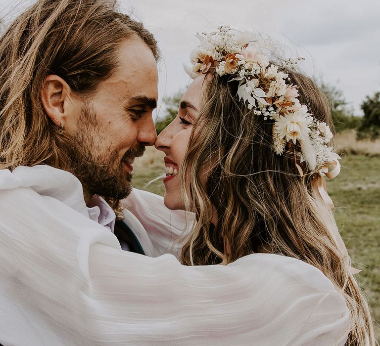 Bride wears floral crown and embraces her groom outdoors on their wedding day