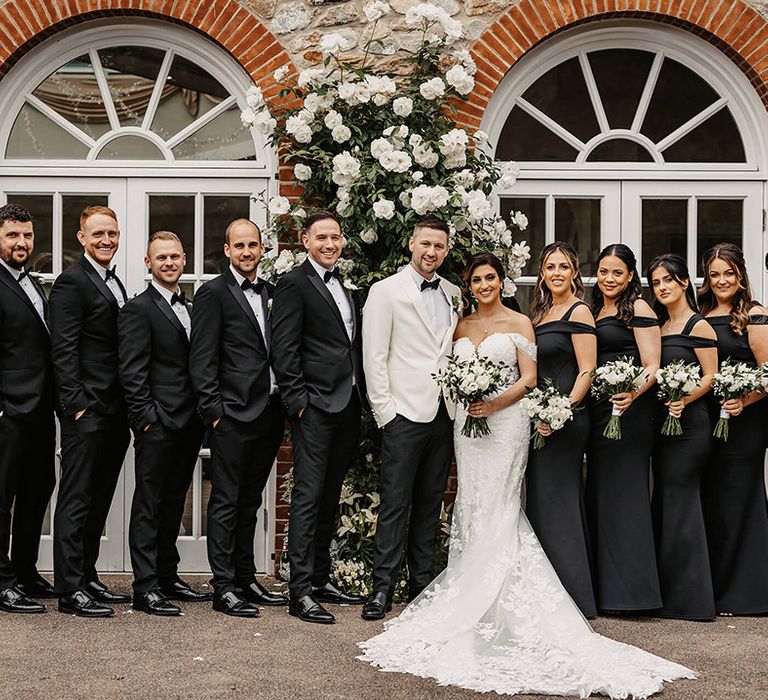 Monochrome wedding party with the bridesmaids in black one shoulder dresses and the groomsmen in black tie for the traditional wedding 