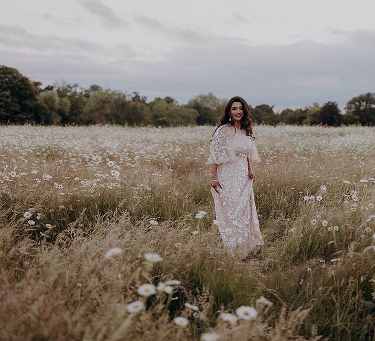 Bride wears embellished batwing Needle & Thread reception dress whilst stood in fields 