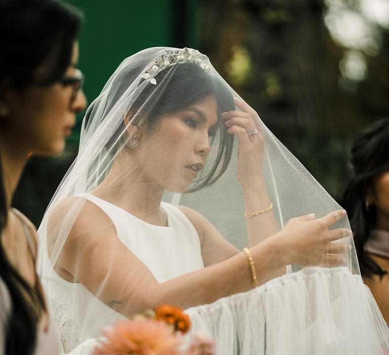 East Asian bride wears drop veil over bridal crown complete with ruffled styling to the edge 