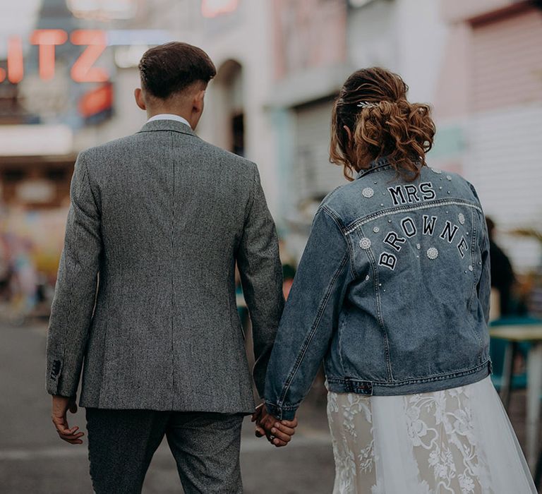 Bride in personalised denim jacket with "Mrs Browne" lettering and pearl detailing 