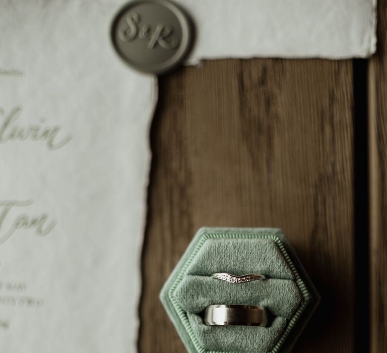 Sage green velvet hexagonal velvet ring box with silver wedding bands for the bride and groom 