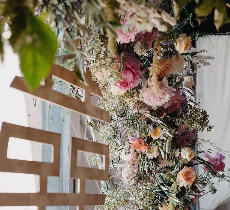 Chinese double happiness symbol hangs from pastel floral arch 