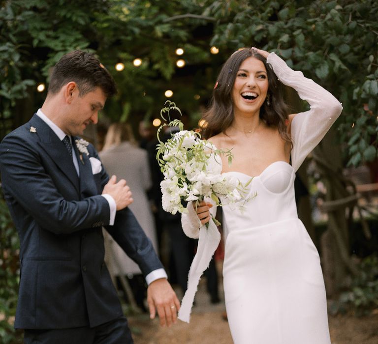 The bride and groom smile together as they brush off the confetti for their rustic wedding