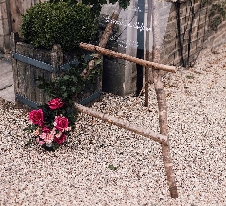 Acrylic wedding sign welcoming the wedding guests to the Cripps Barn wedding on rustic tree branch easel