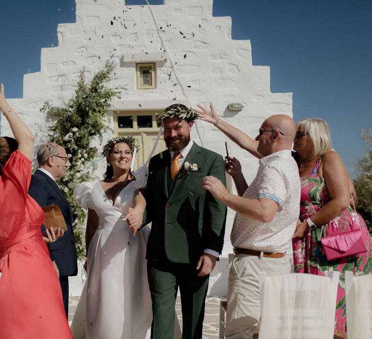 Bride and groom smiling during their confetti exit from intimate wedding ceremony in Paros, Greece