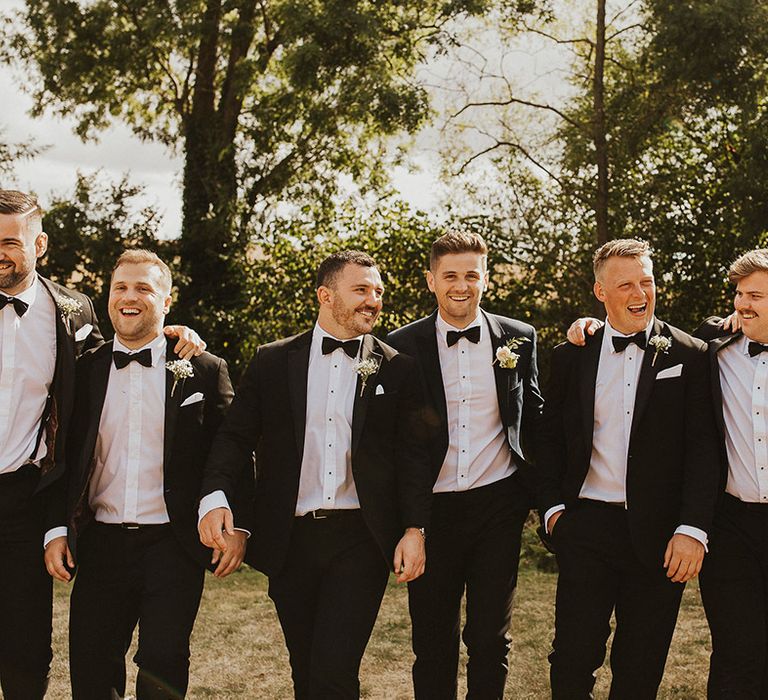 Groomsmen and the groom in matching black tie for the wedding 