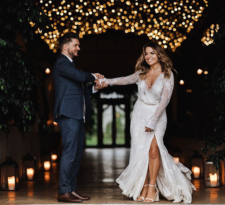 Bride in sparkly long sleeve lace winter wedding dress with white block heels on her feet being spun by the groom at their snowy Stone Barn wedding