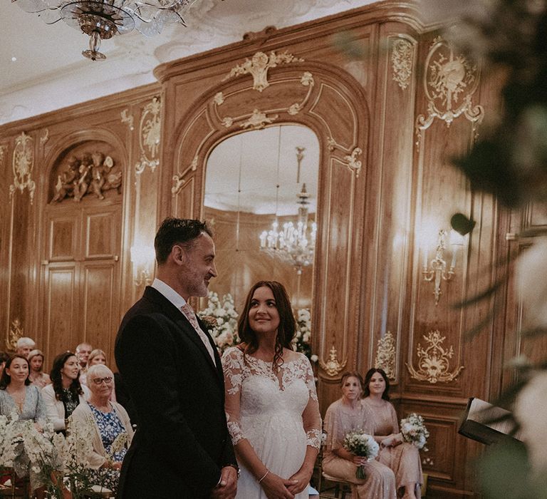 Claridge's wedding in London with the pregnant bride gazing up at the groom during the ceremony 