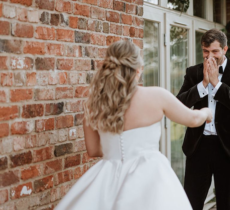 Groom is blown away and starts to cry as he sees the bride in her incredible Suzanne Neville wedding dress for the classic country house wedding at Doddington Hall and Gardens