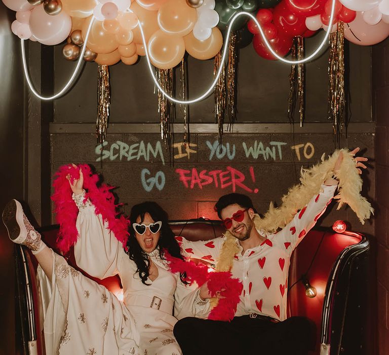 Bride in Bowen Dryden sparkly white jumpsuit with retro white sunglasses and groom in love heart shirt with red sunglasses 